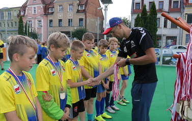 Zdjęcie przedstawia zawodnik&oacute;w na boisku po meczy jak trener gratuluje zwycięstwa