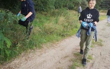 Zdjęcie przedstawia chłopc&oacute;w zbierających śmieci