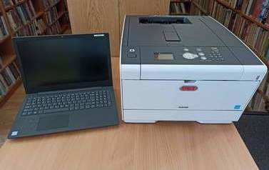 Zdjęcie przedstawia drukarkę laserową OKI i laptopa Lenovo