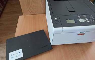 Zdjęcie przedstawia drukarkę laserową OKI i laptopa Lenovo