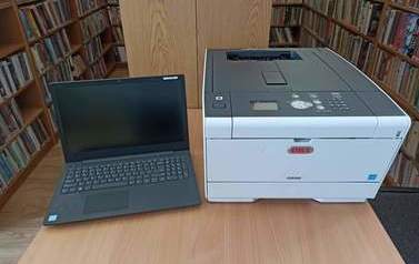 Zdjęcie przedstawia drukarkę laserową OKI i laptopa