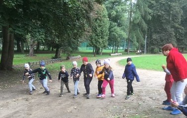 Grupa dzieci w wieku 6lat biegnących przez las